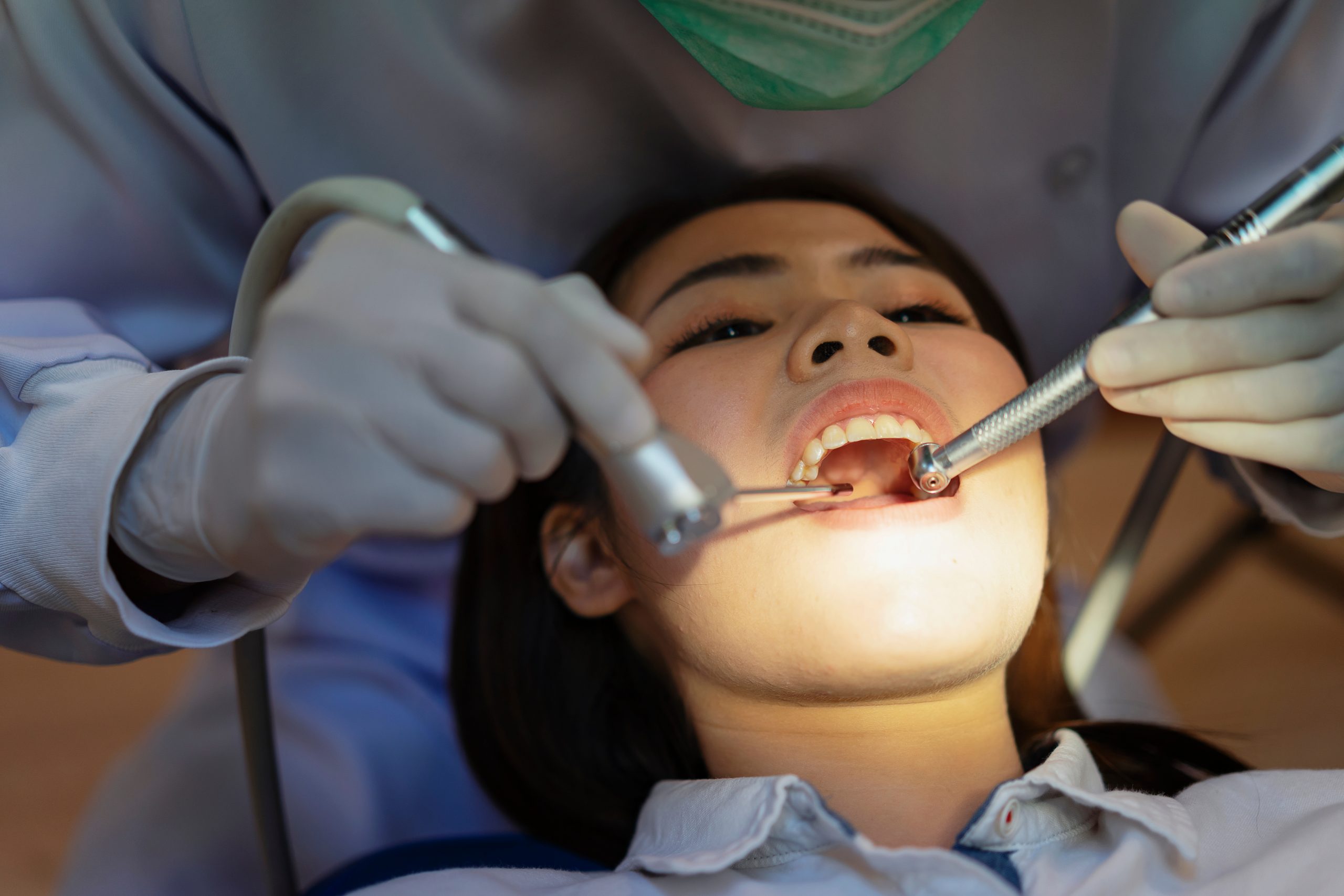 A dentist holding tools in a patient's mouth.