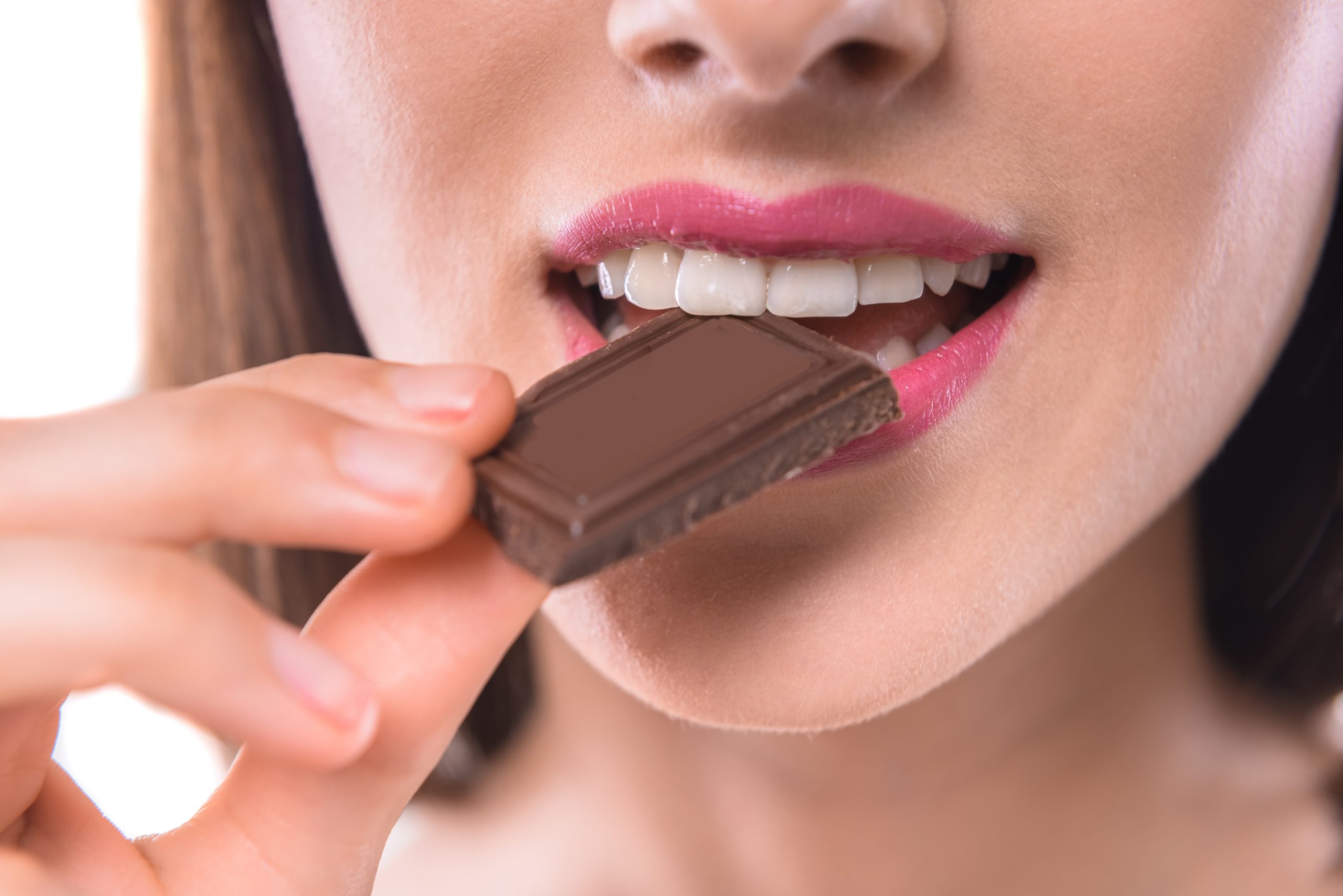 Closeup view of a woman taking a small bite of chocolate.