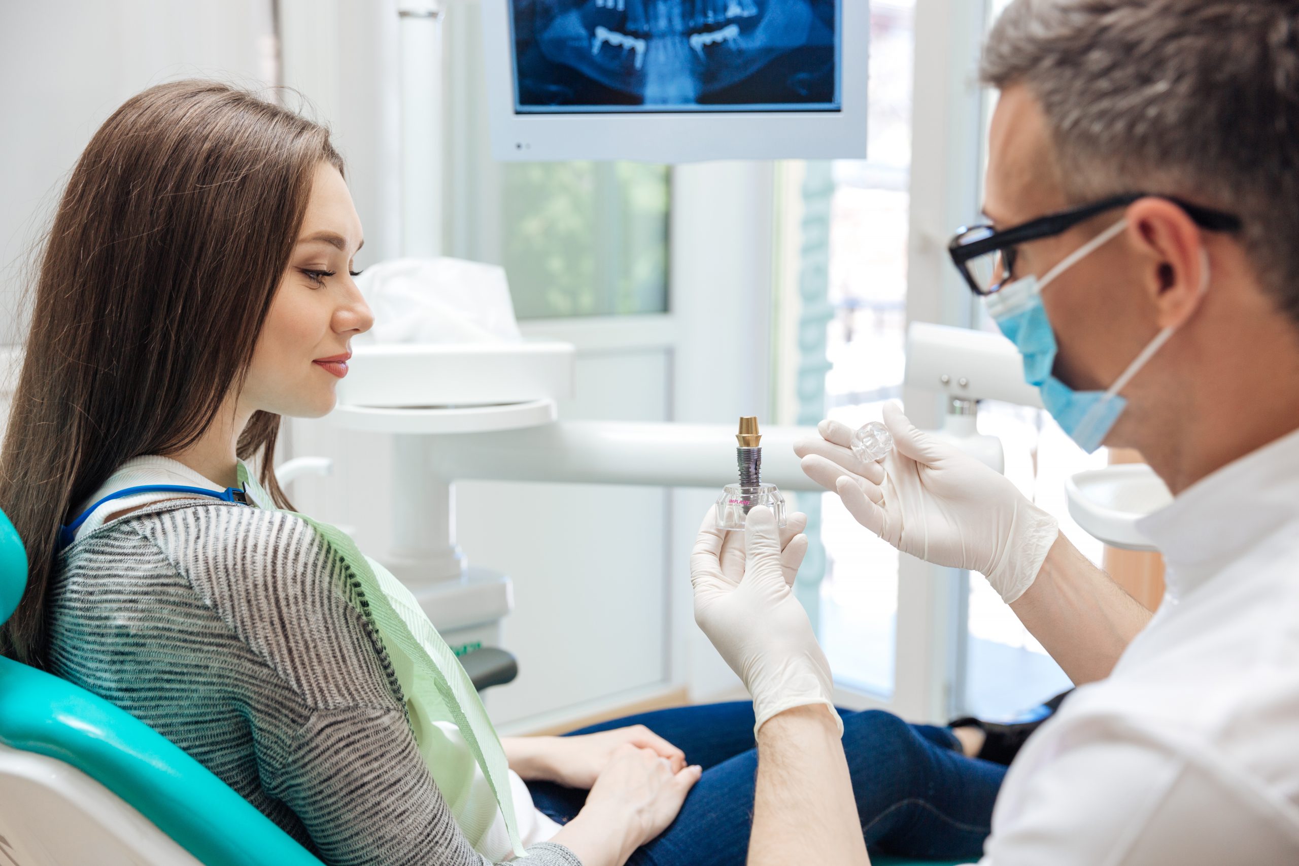 Dentist showing patient the components of a dental implant.